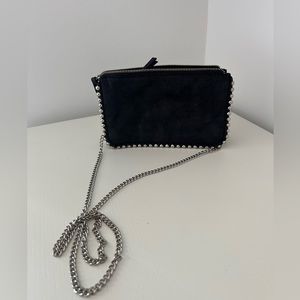 Trendy black clutch with metallic details and long chain.